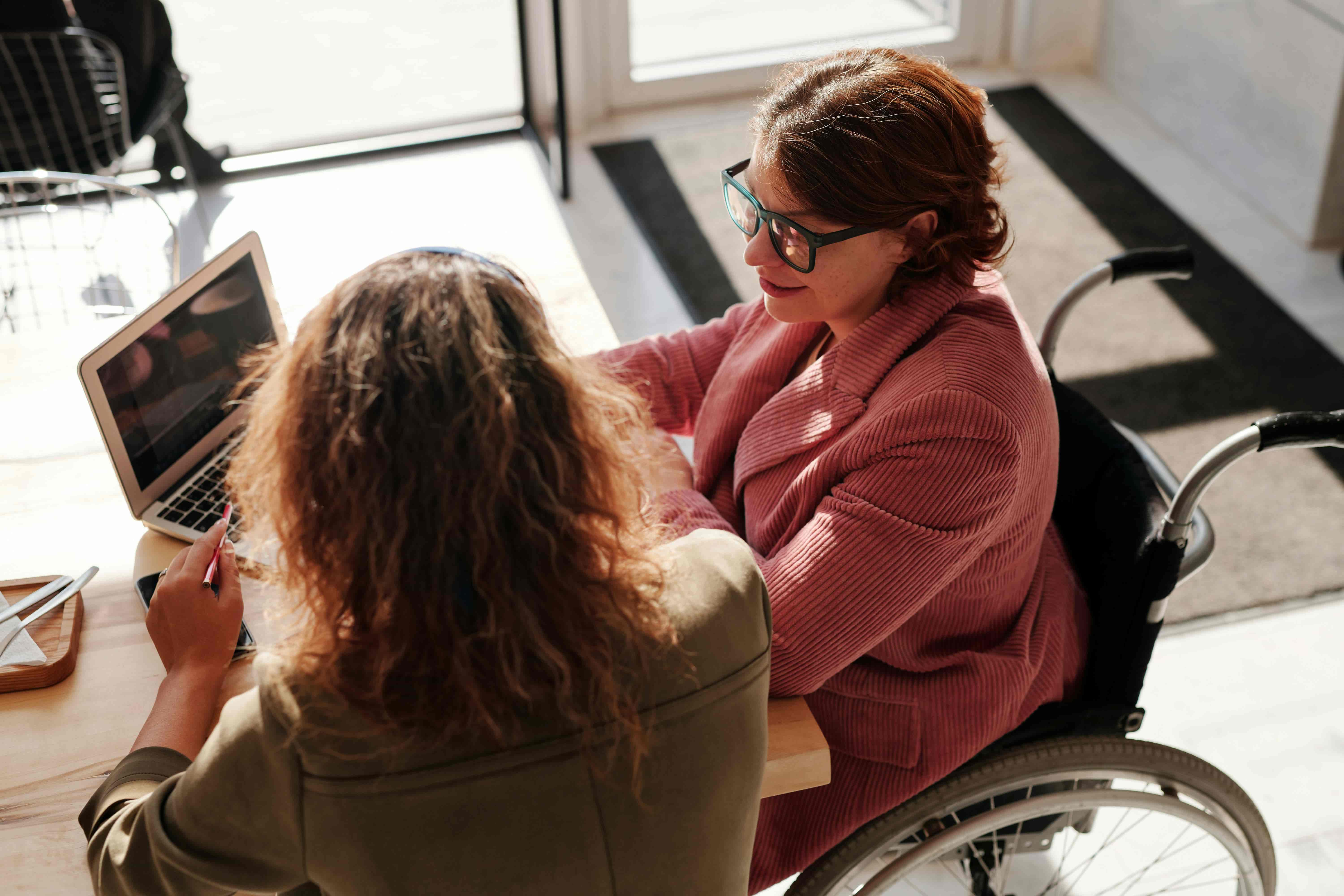 A woman on a wheelchair talking to her therapist